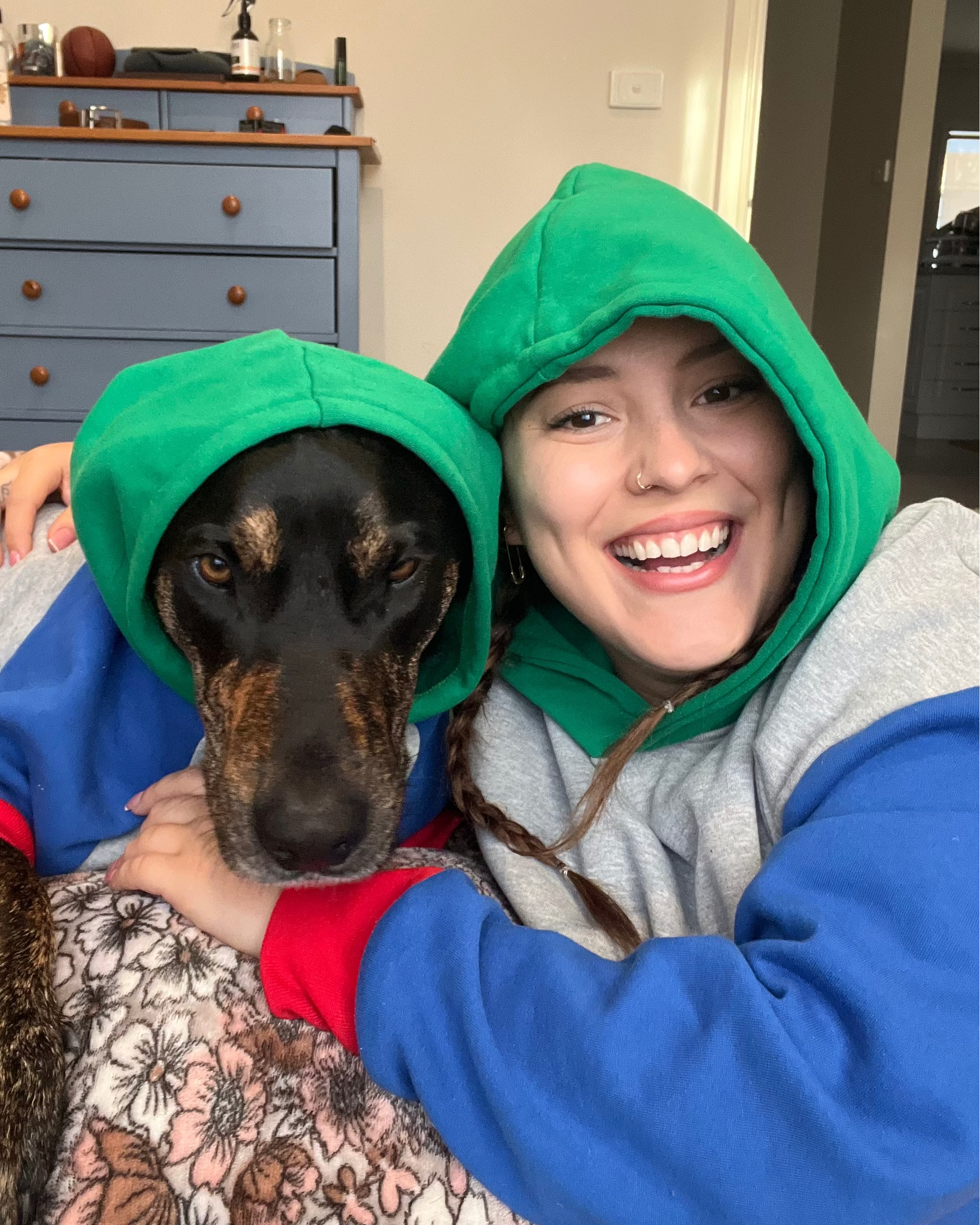 Person and dog wearing green hoodies in a home setting